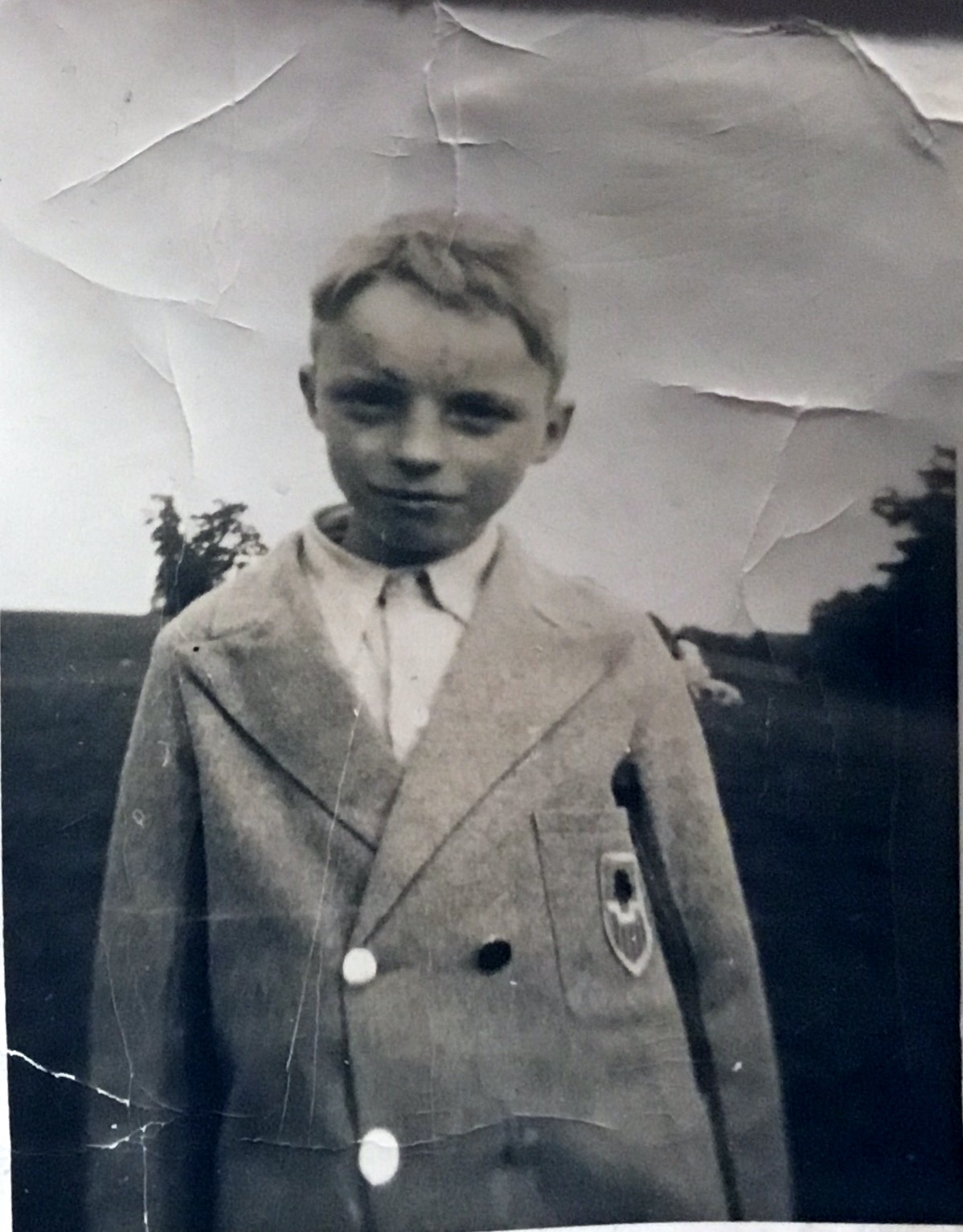 As a child, possibly in school blazer, which looks to be far too big for him.  It has odd buttons too.  Possibly around 1940