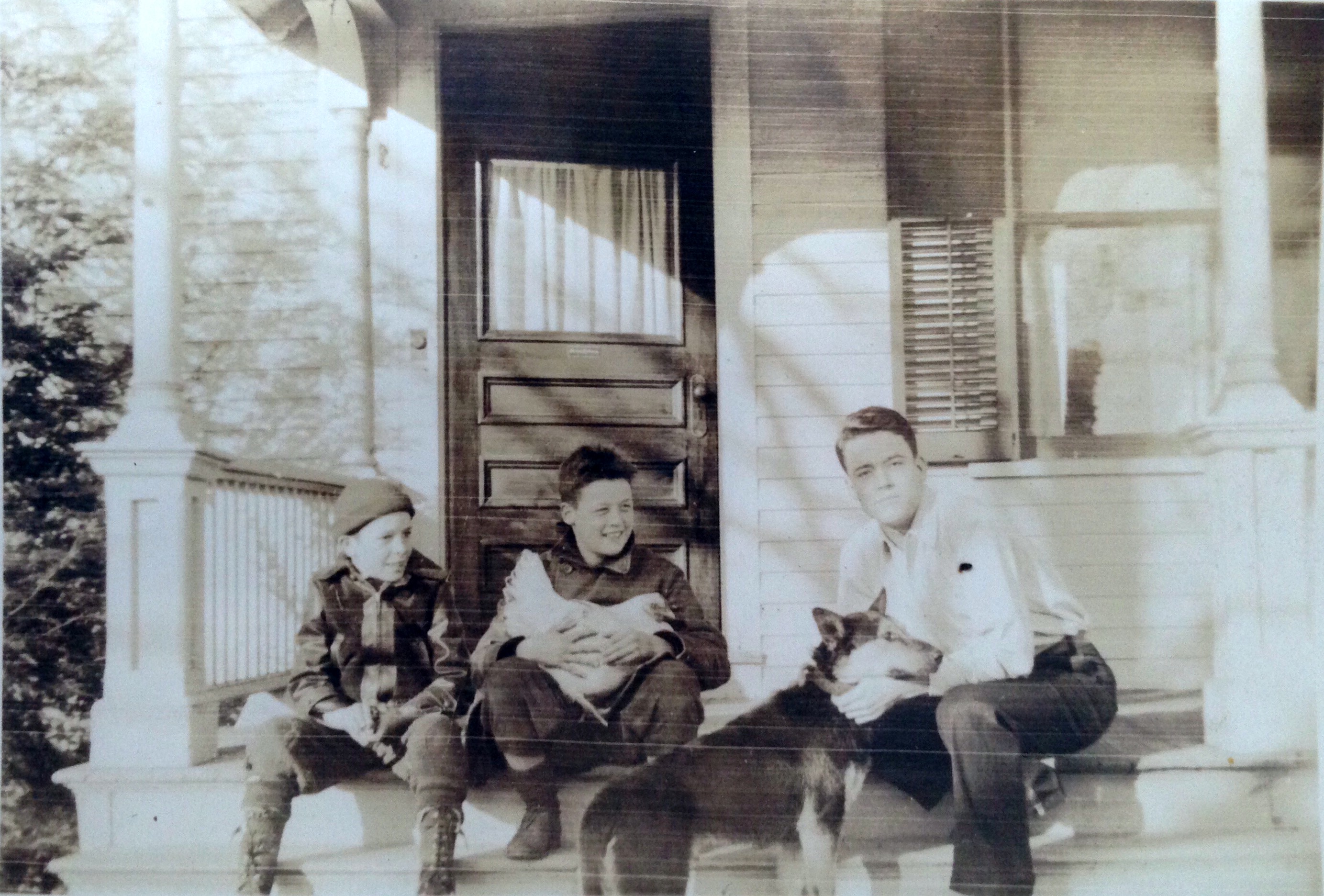 Posing on the porch, January 1938: my father(with chicken) and his older brother in Orange, CT.