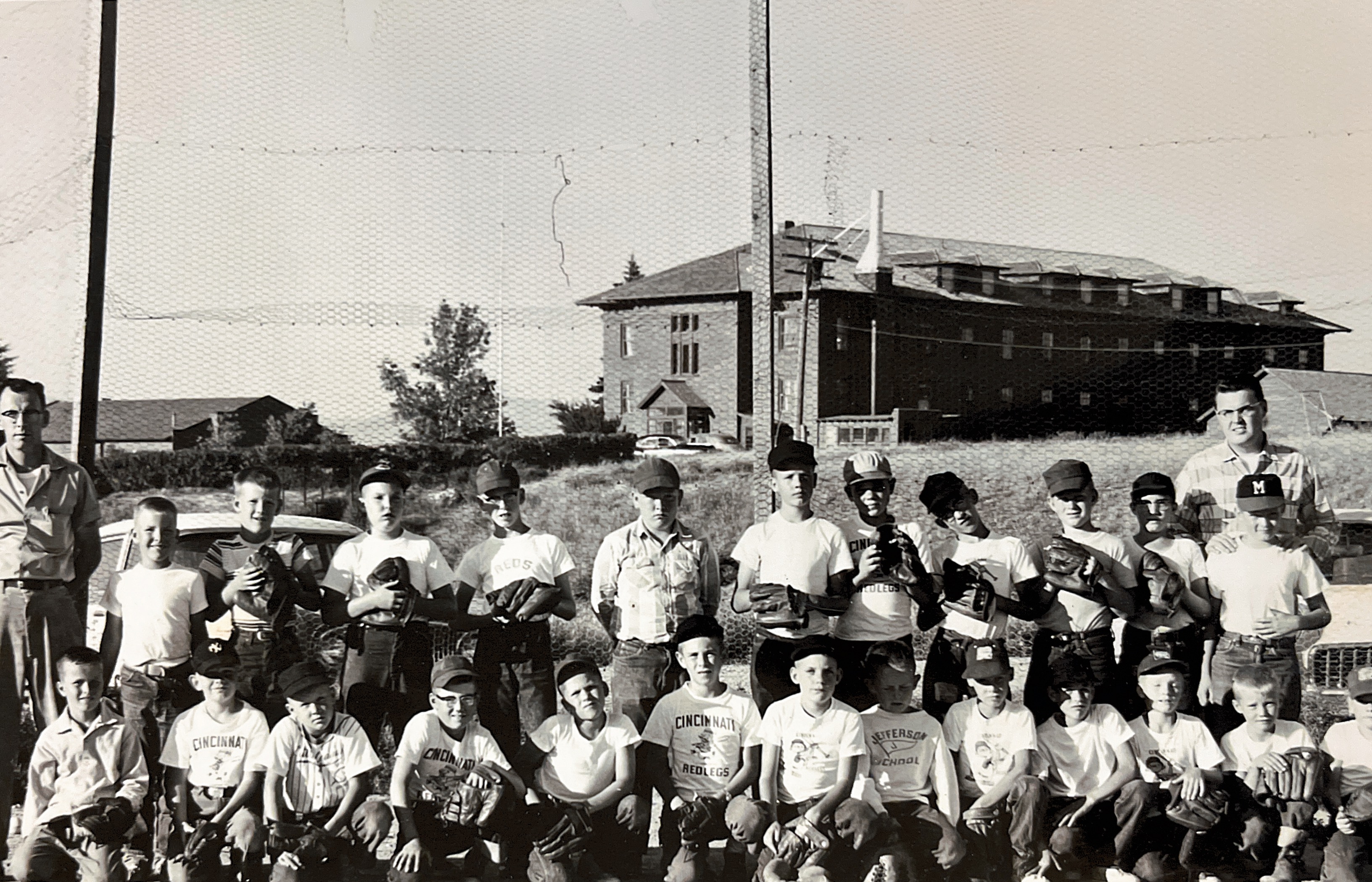 Star Motel Field approximately 1957ish. Corner of 9th and Sanders, Helena, MT. Mike is at end of top row on far right, Tom is right below him. Rick is 4th from left bottom row, Mike McGinley is far L bottom row. Grandpa Jack Nilan is coach on left.  Grandpa Jacks car was a 1955 Chevy Stationwagon.